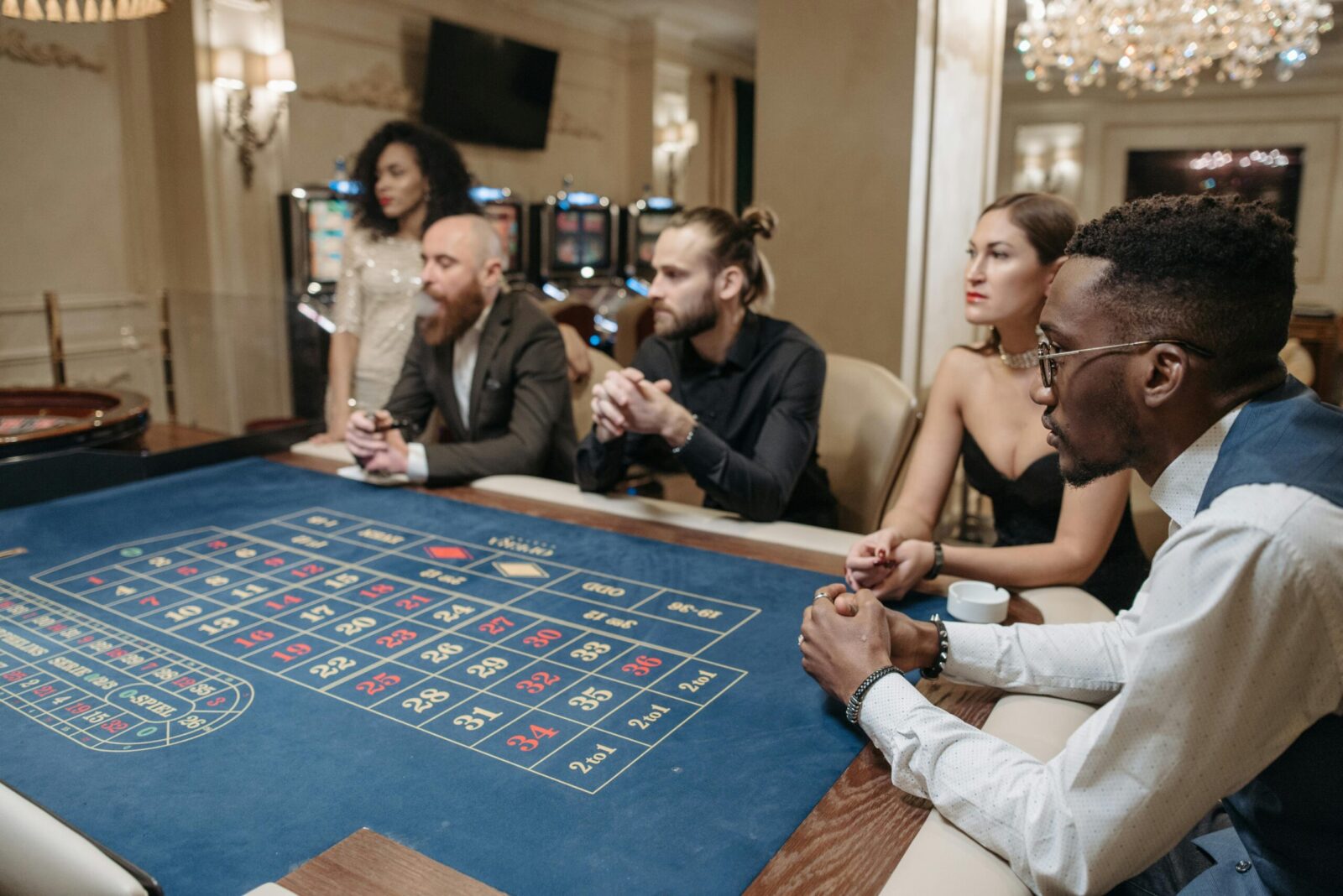 A diverse group of adults engaged in a roulette game at a luxurious indoor casino setting.