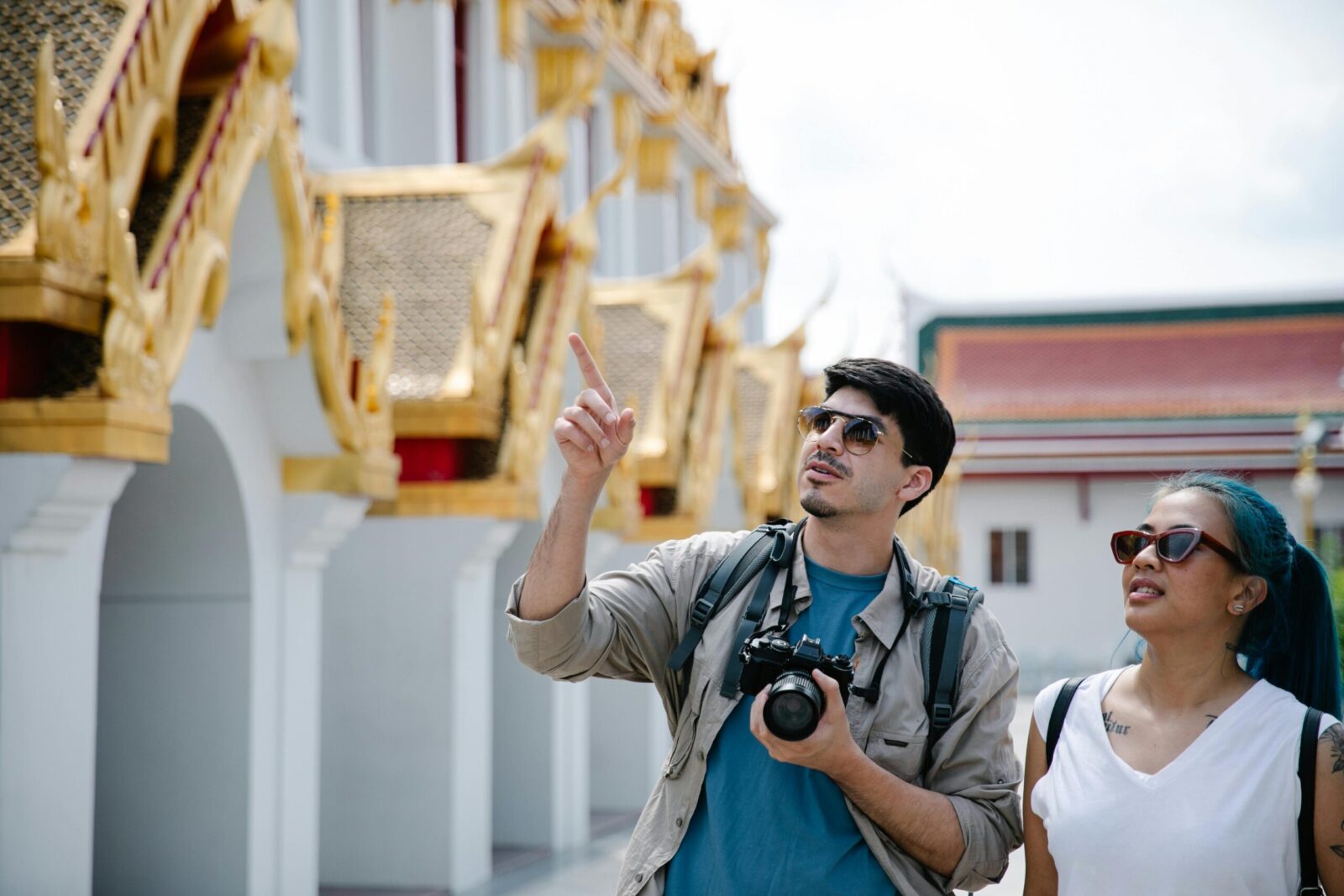 A couple of tourists admire intricate architecture, capturing moments with a Canon camera.